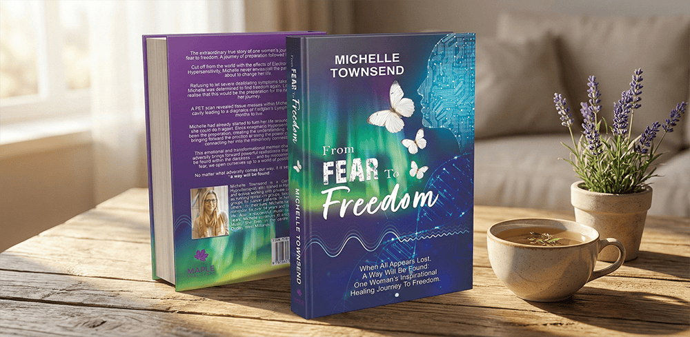 A 3D mockup of the memoir 'From Fear to Freedom' by Michelle Townsend. Two copies of the book are displayed on a sunlit wooden table next to a teacup and a small potted lavender plant, showing the vibrant blue and green cover design featuring white butterflies